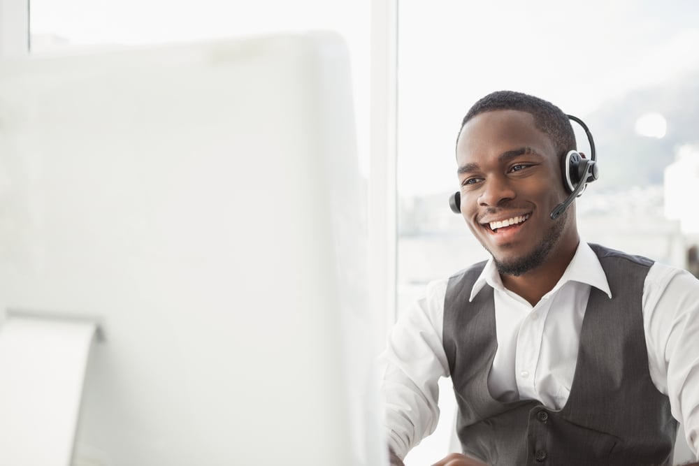 Smiling businessman with headset interacting in his office