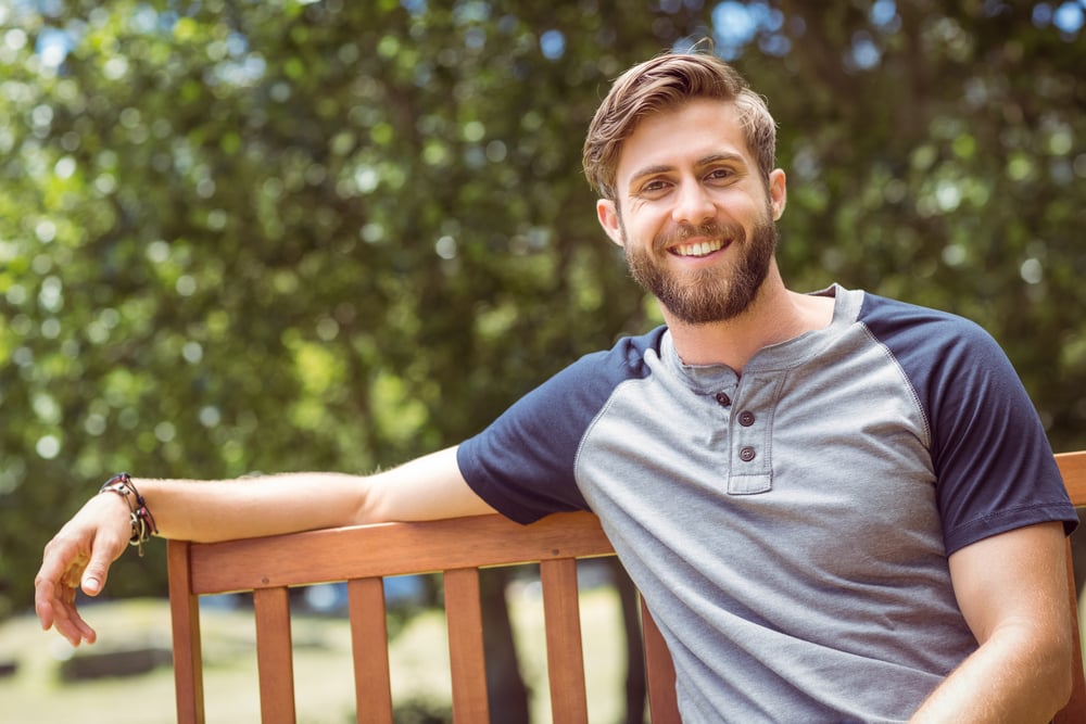 Young man relaxing on park bench on a summers day